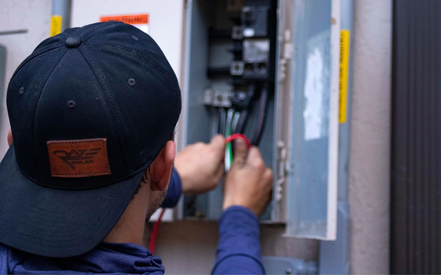 An electrician wiring breakers in a residential electrical panel.