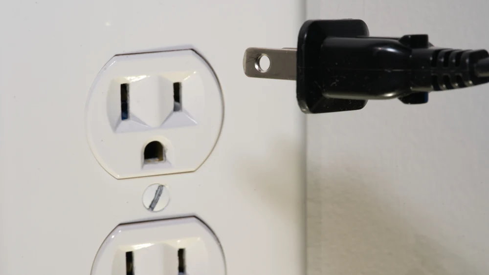 A plug next to a wall outlet.