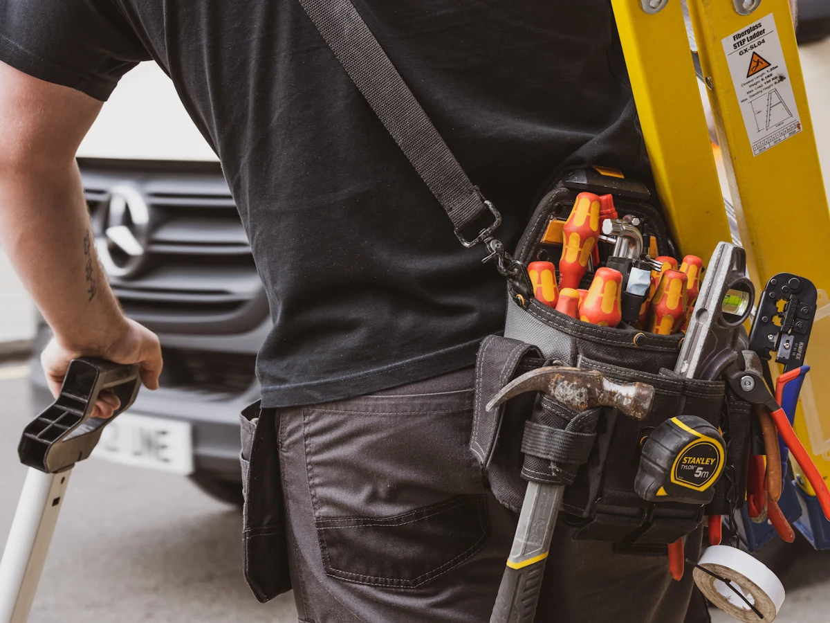 An electrician wearing a tool belt full of hand tools.